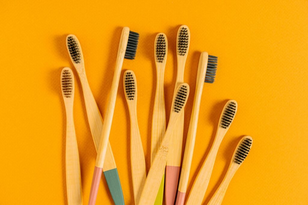 A selection of bamboo toothbrushes arranged on a vibrant yellow background, promoting sustainable living.